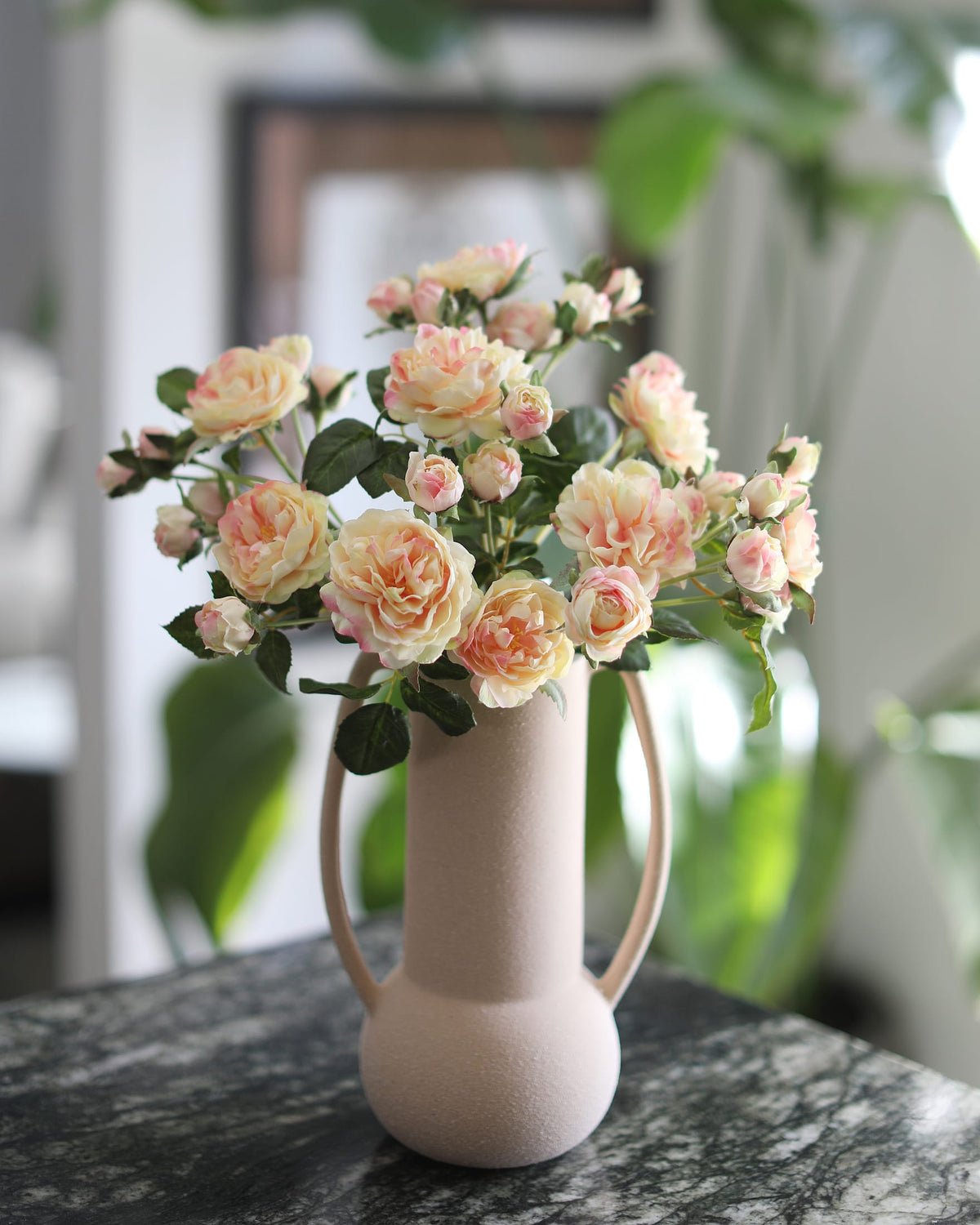 Vase with pink and yellow faux flowers on a marble surface