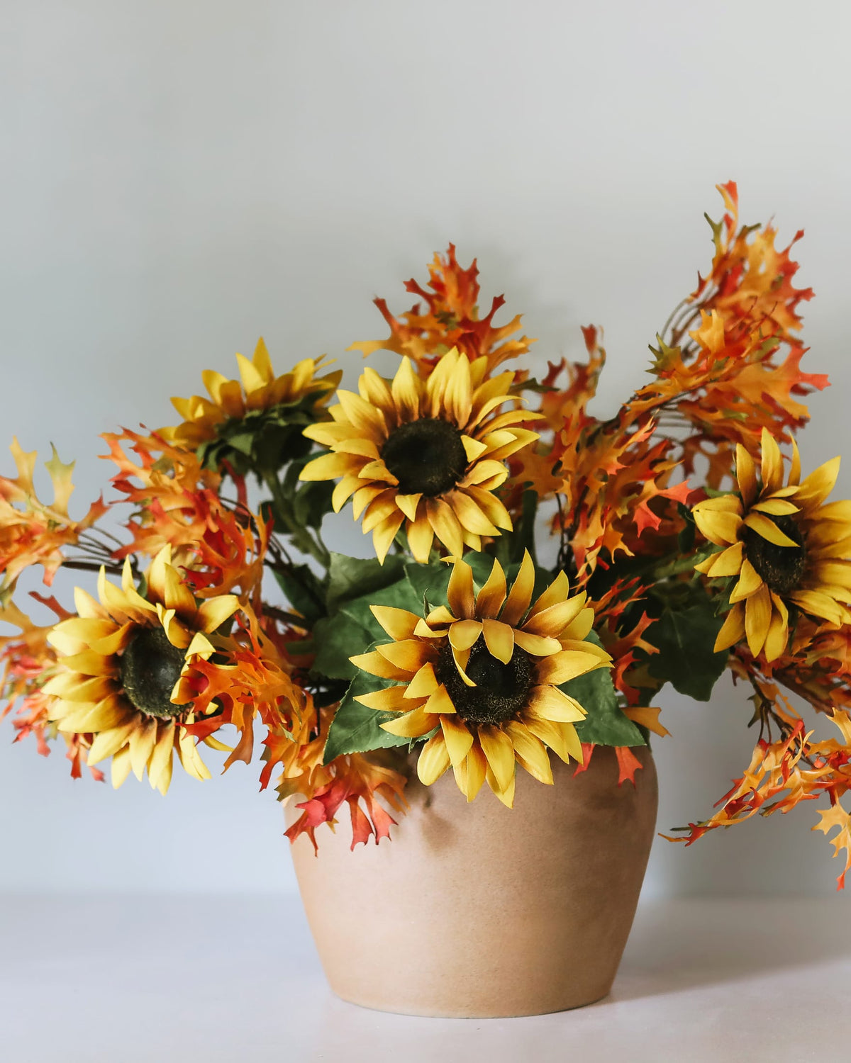 faux sunflowers and oak leaves in a vase