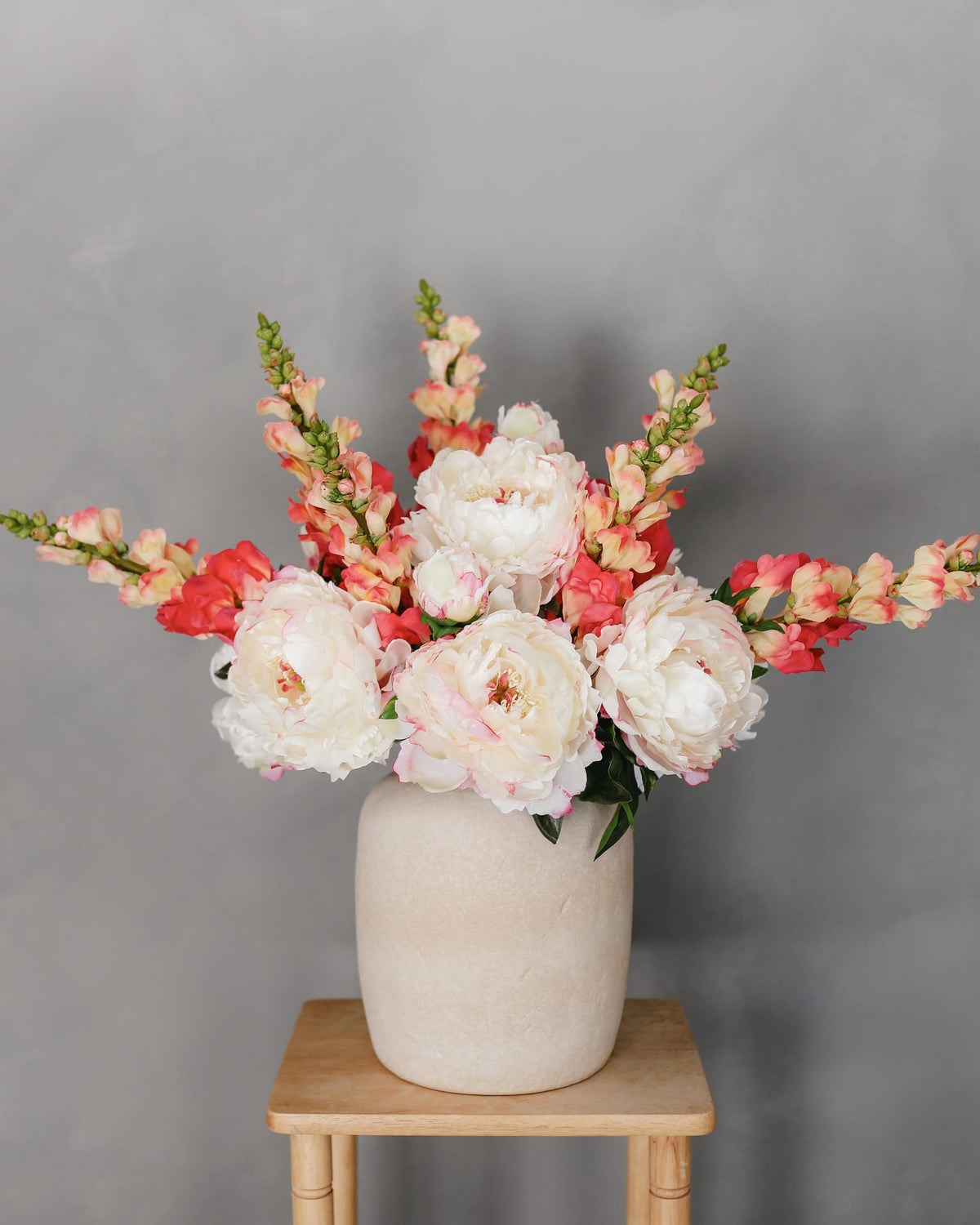 faux peonies and coral snapdragon stems in a vase 