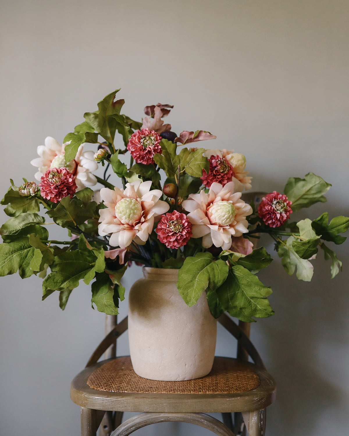 artificial flower arrangement of fig, waratah and dahlia in a vase