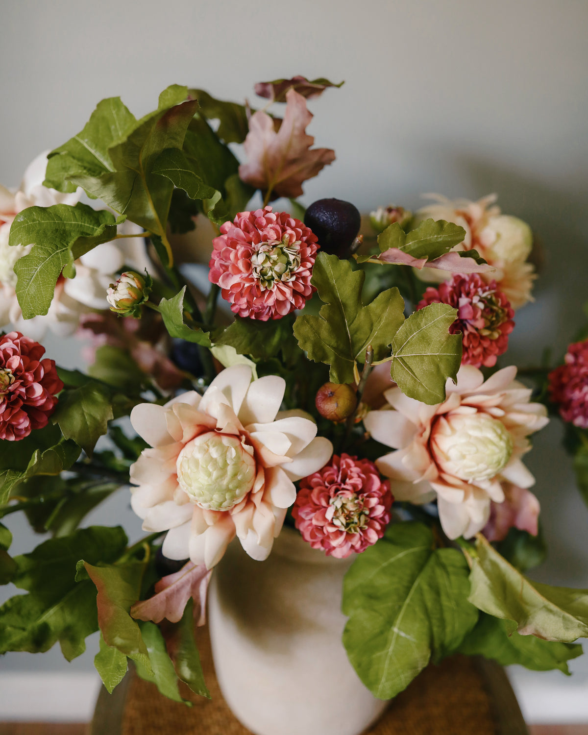 artificial flower arrangement of fig, waratah and dahlia in a vase