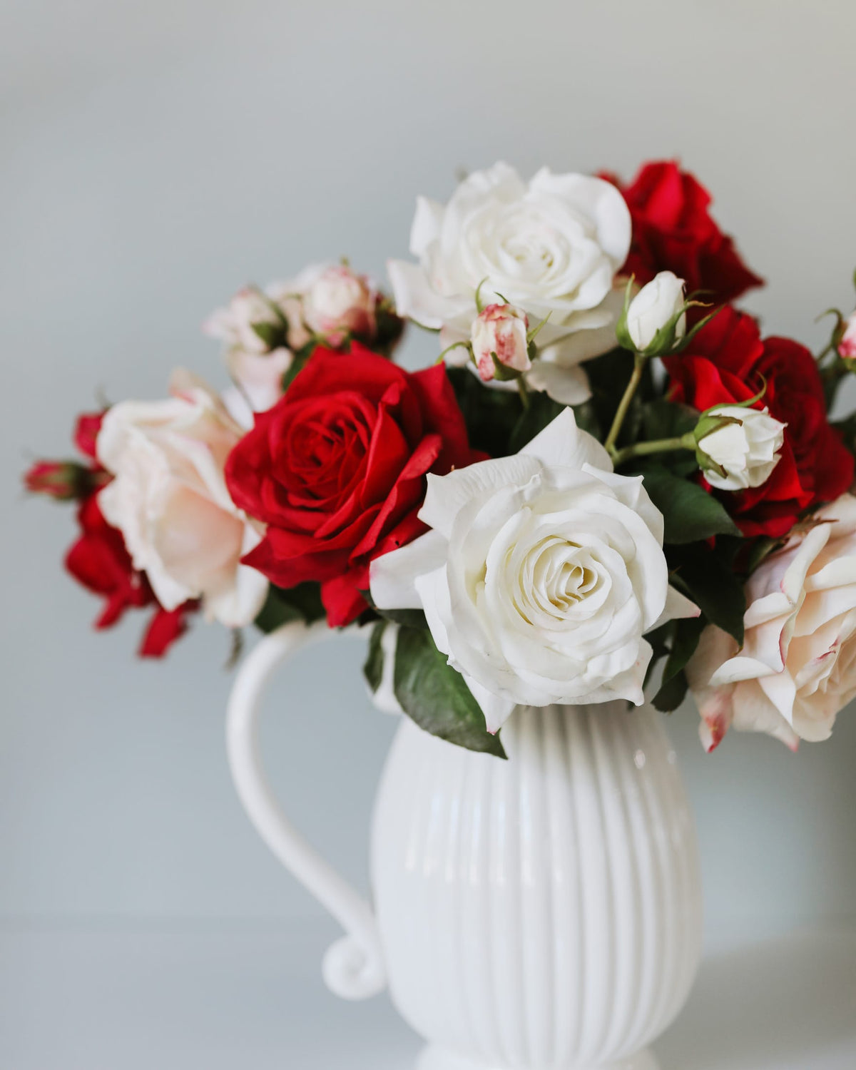 red, white a pink faux real touch roses in a vase