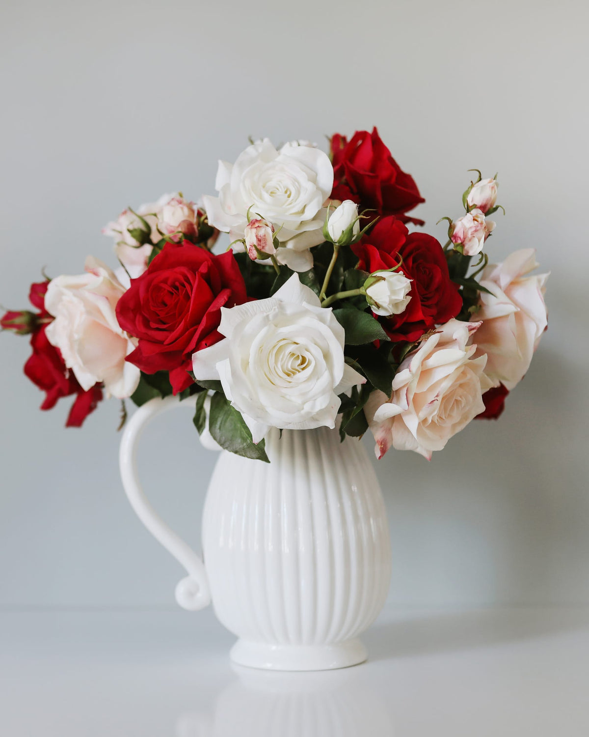 Faux white, red and pink real touch roses in a white vase