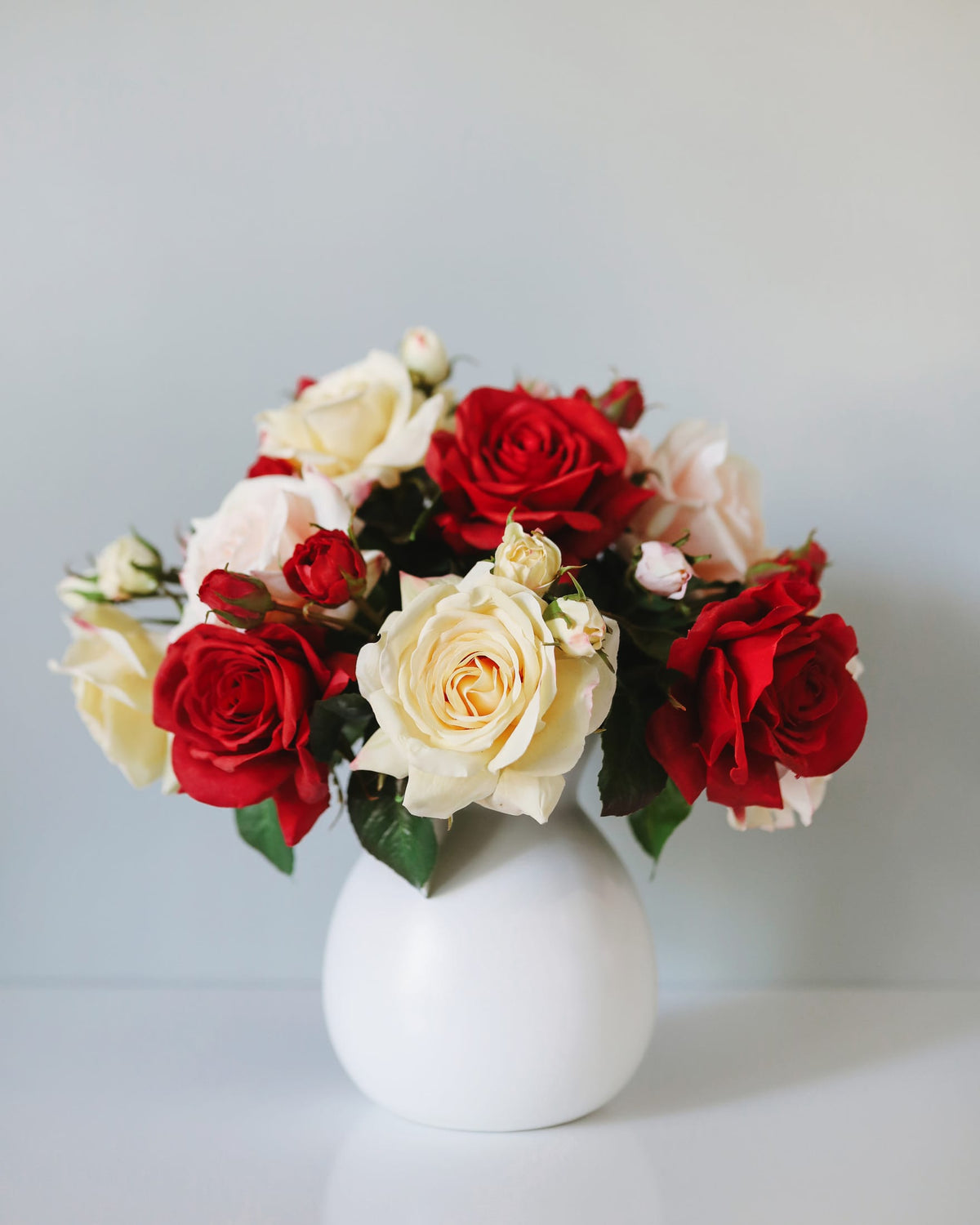 artificial red, white, yellow and pink real touch roses in a vase