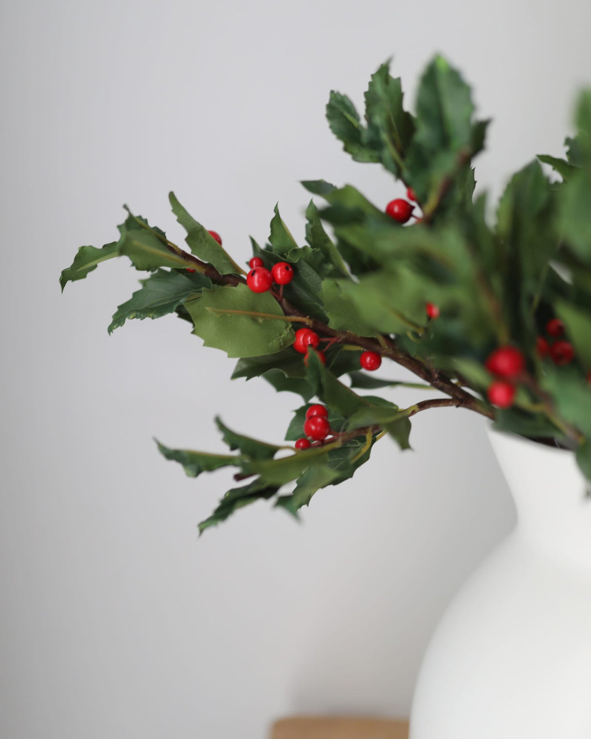 faux holly stem in a vase