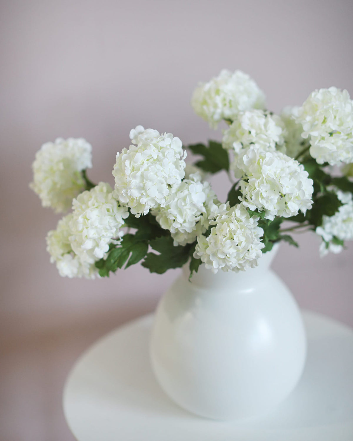 artificial snowballs in a white vase on a blurred background