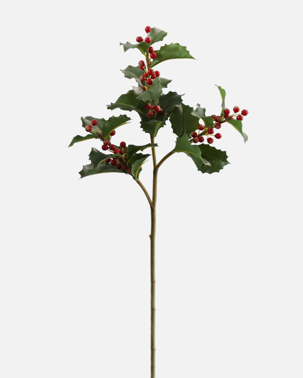 An artificial holly stem with dark green leaves and clusters of small red berries, isolated on a light gray background.