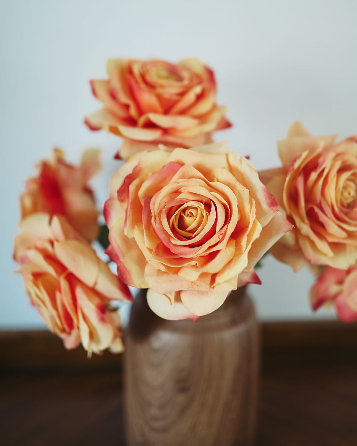 Bouquet of peach-colored roses in a clear vase against a light background