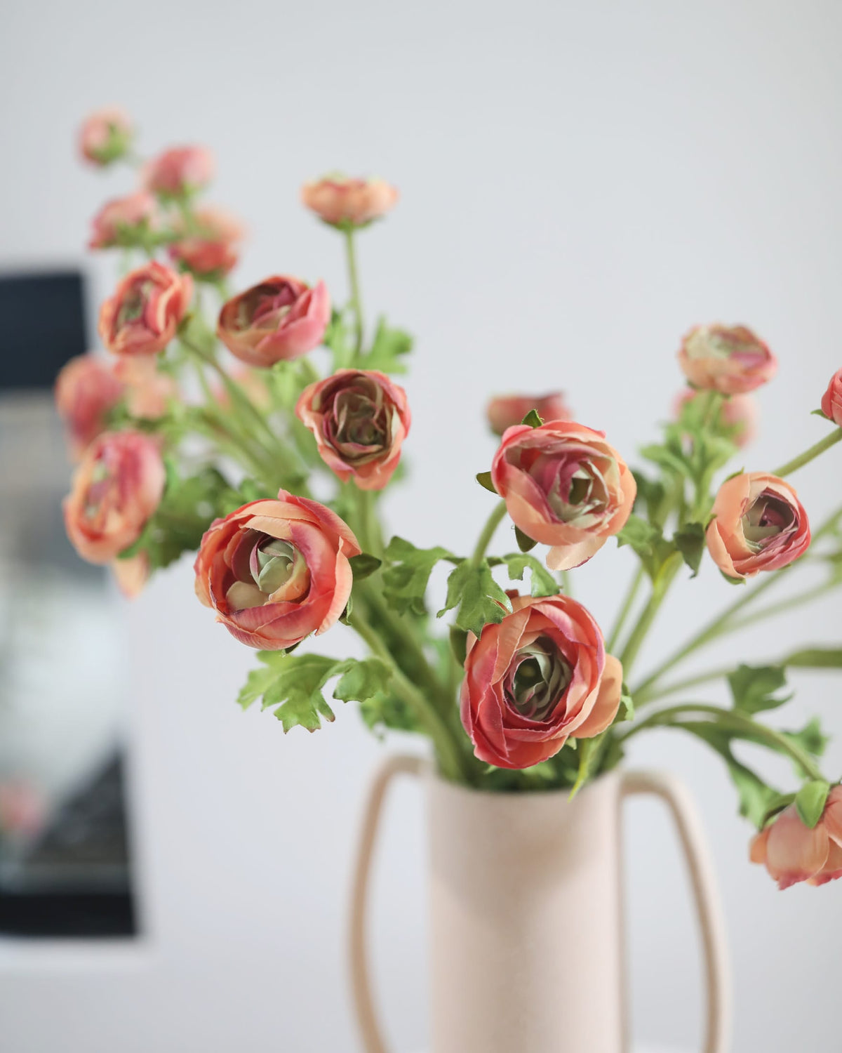  faux pink ranunculus in a vase on a blurred background