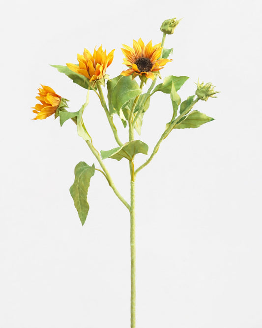 A single artificial sunflower stem with three yellow-orange flower heads, green leaves, and closed buds on a plain light gray background.