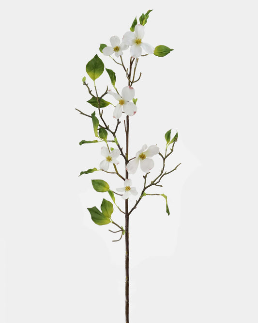 A single artificial flowering dogwood branch with white blossoms, green leaves, and brown stems on a plain light gray background.