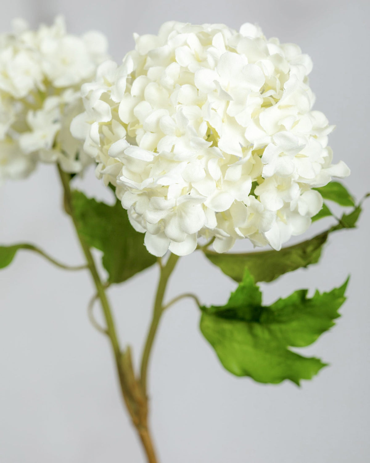 White artificial snowball with green leaves on a light gray background