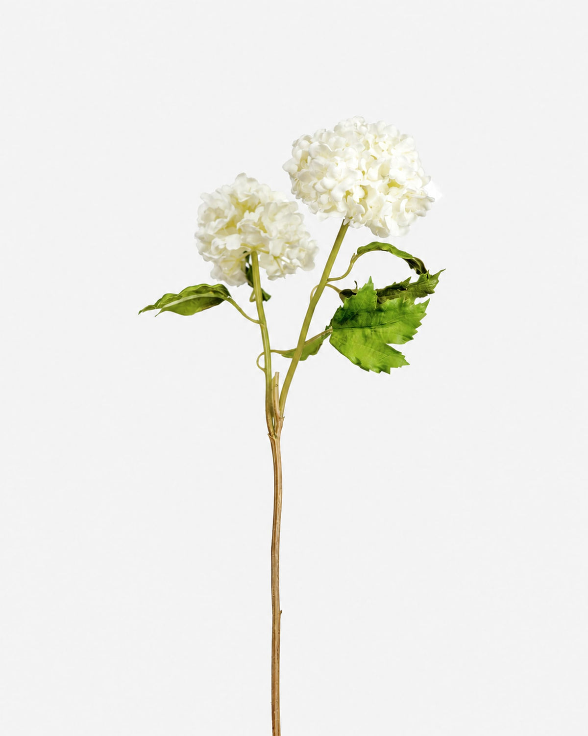 A single artificial snowball stem with two white fluffy blooms, green leaves, and a long brown stem, photographed against a plain light gray background.