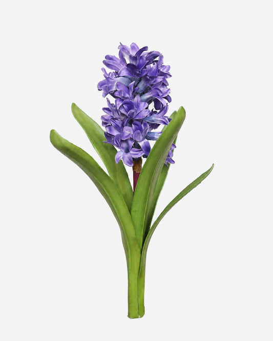 A single artificial hyacinth flower with a dense cluster of purple-blue blossoms and green leaves on a plain light gray background.