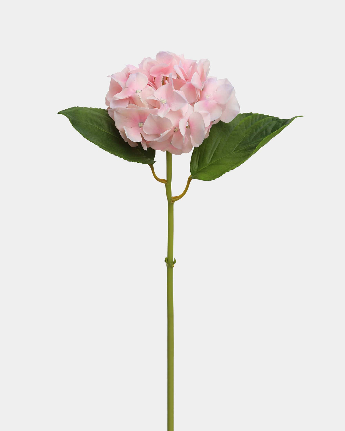 A single artificial pink hydrangea flower with green leaves and a long green stem, photographed against a plain light gray background.