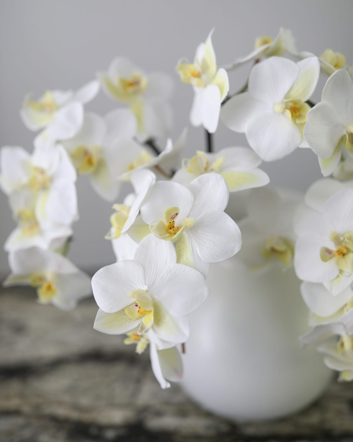 Artificial white Phalaenopsis orchids arranged in a vase for sophisticated home decor.