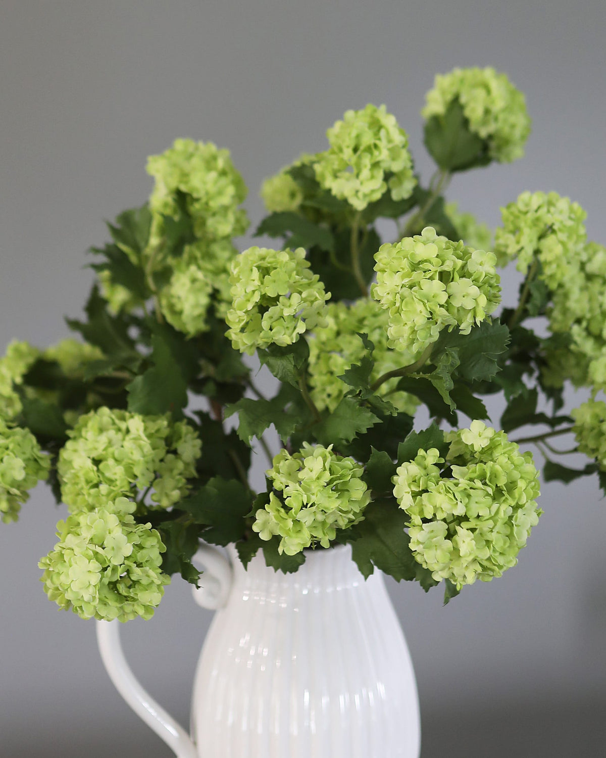 Green Faux Snowballs in a vase close up 