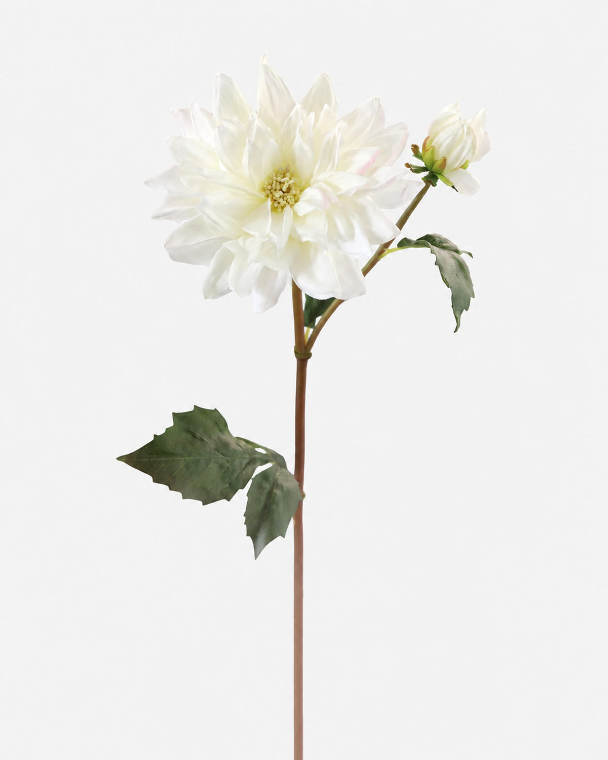 A single white faux dahlia flower stem with green leaves and a small bud, photographed against a plain light gray background.