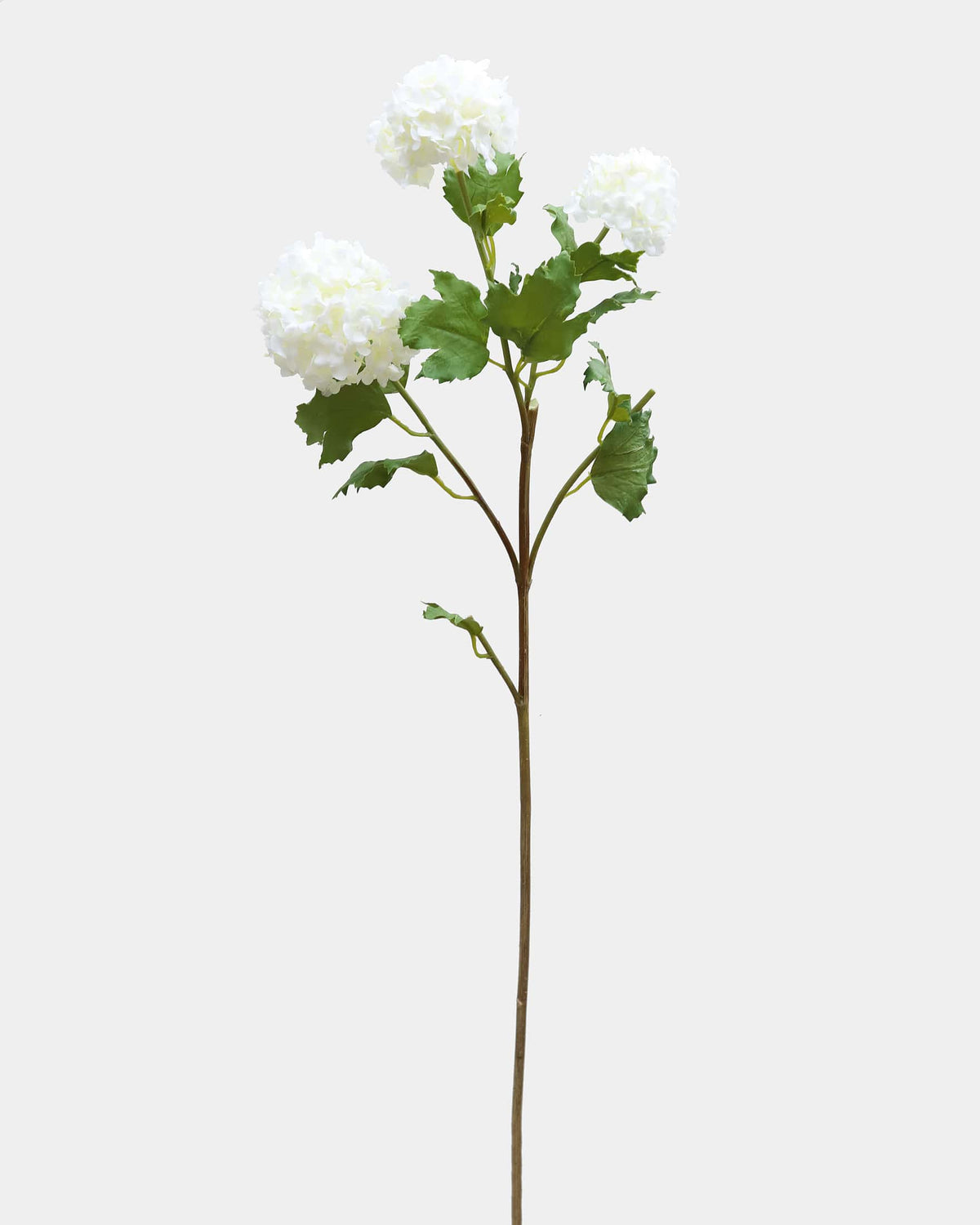 A single artificial snowball stem with three white hydrangea-like blooms, green leaves, and a long brown stem on a plain light gray background.