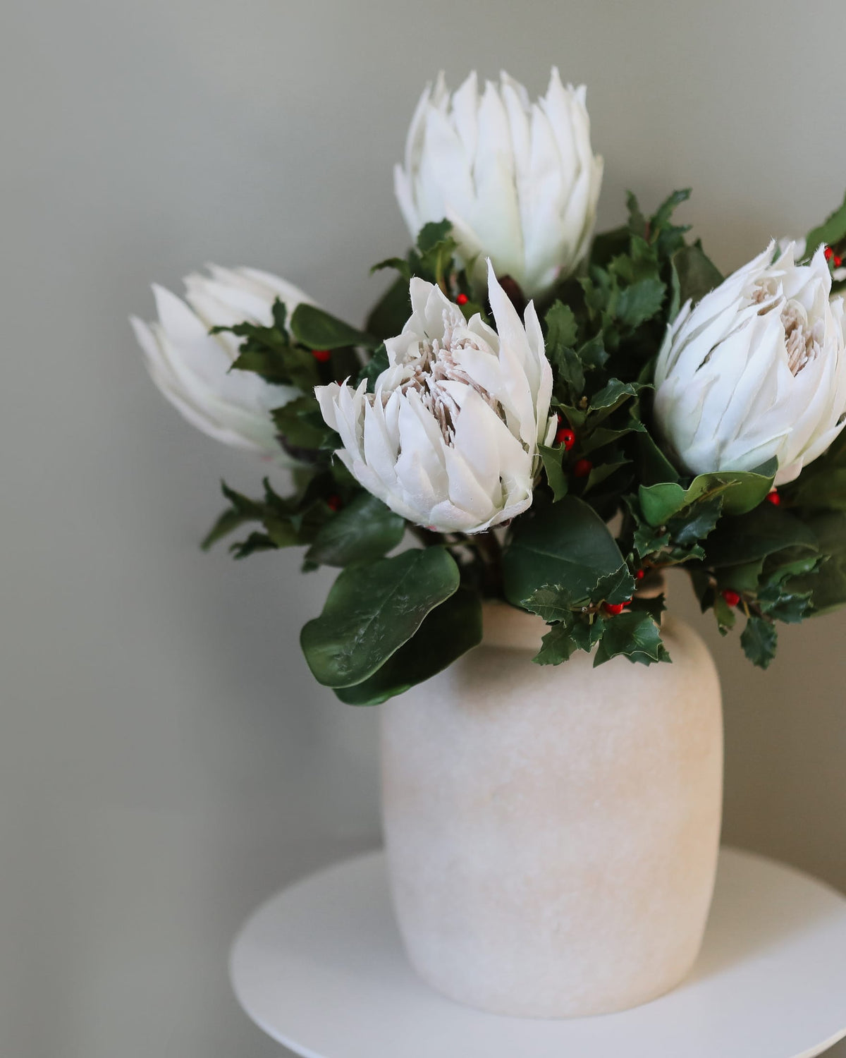 faux white proteas and holly in a vase